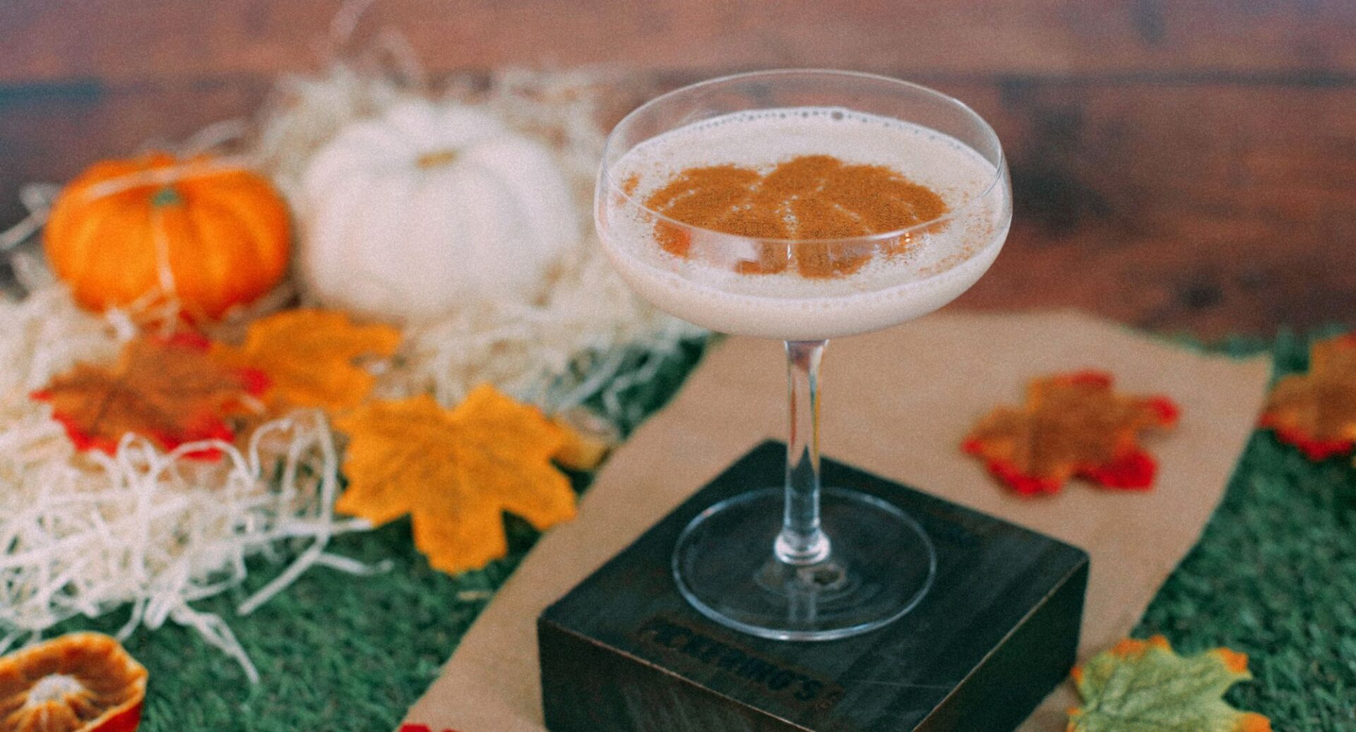 Close-up of a cream cocktail, with pumpkins and autumn leaves in the background.