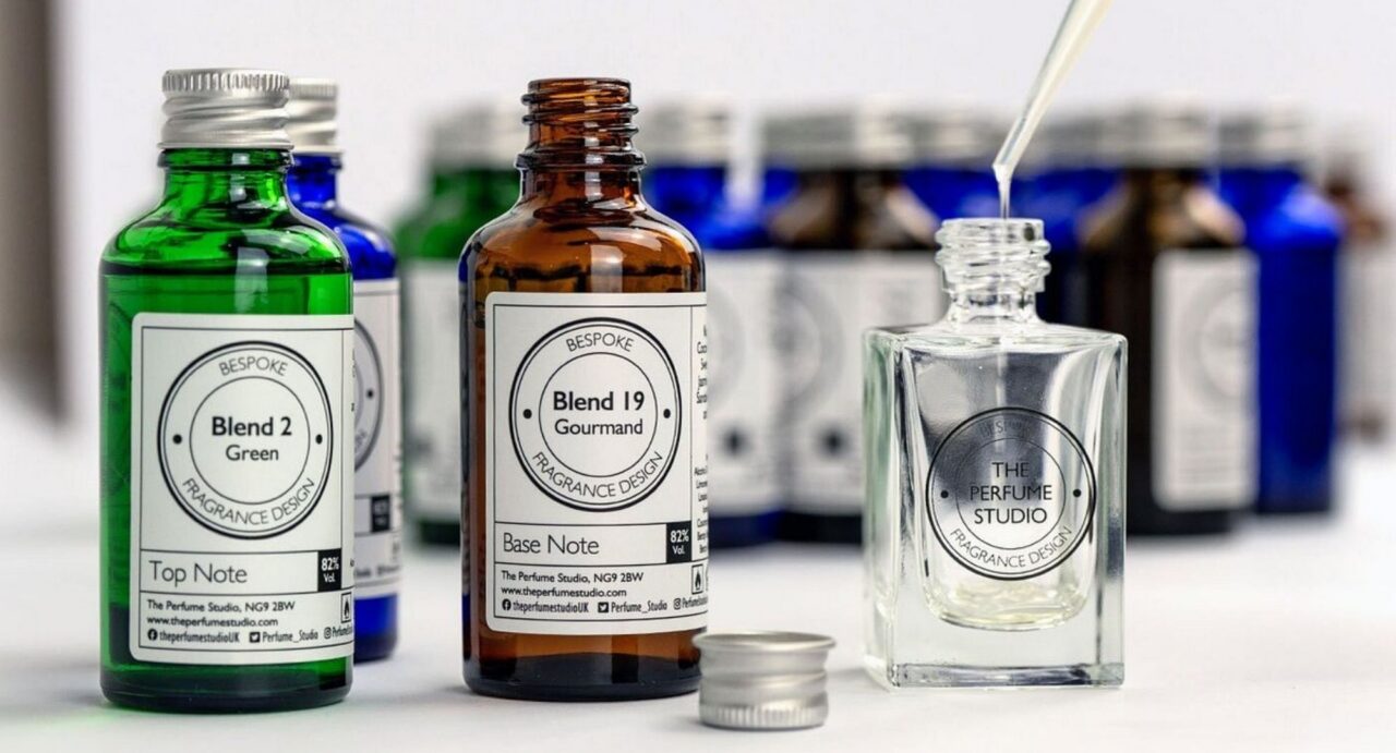 4 small glass bottles on a counter: one green, one blue, one brown and one clear.