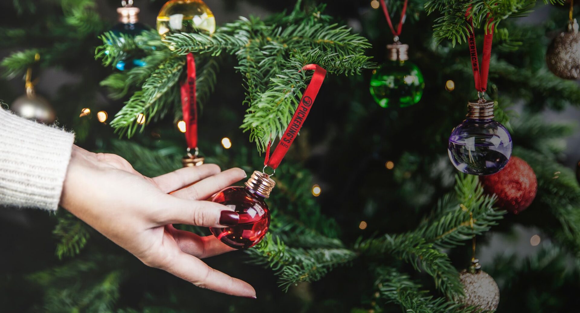 Close-up of a Christmas tree, with glass gin-filled baubles hanging from the branches.