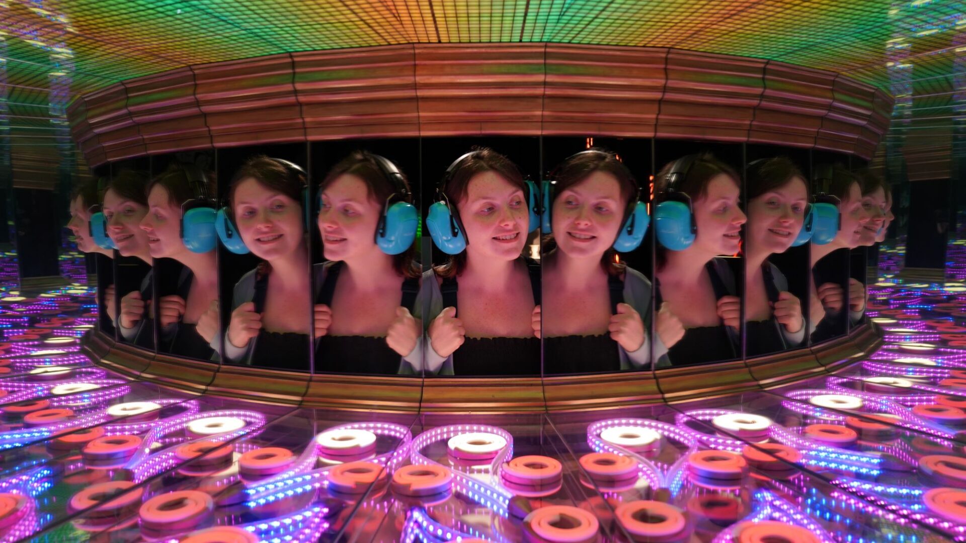 A girl in ear defenders looks in the Perpetual Portrait exhibit at Camera Obscura & World of Illusions, Edinburgh