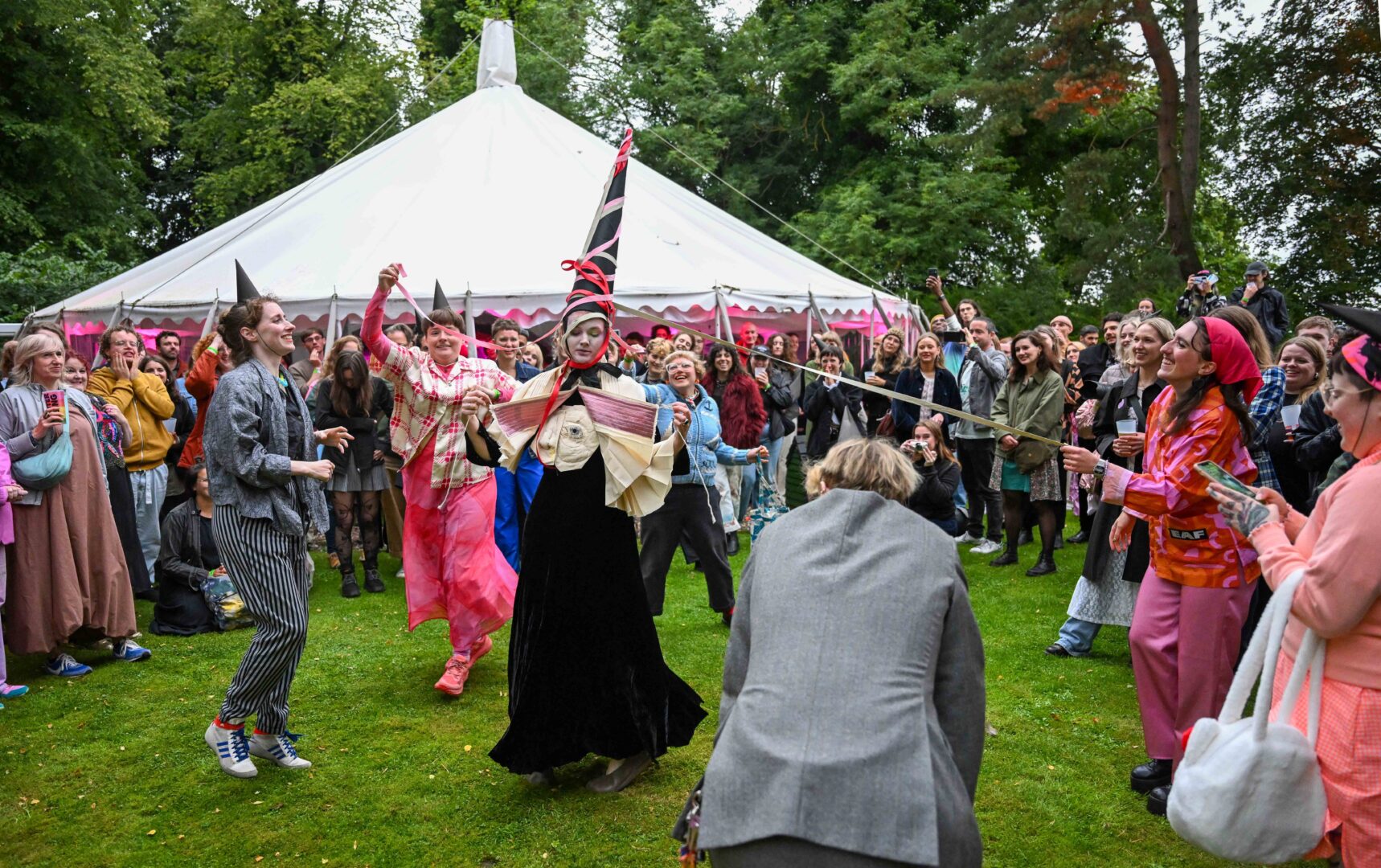 Two women dressing up and dancing in the middle of a crowd outside