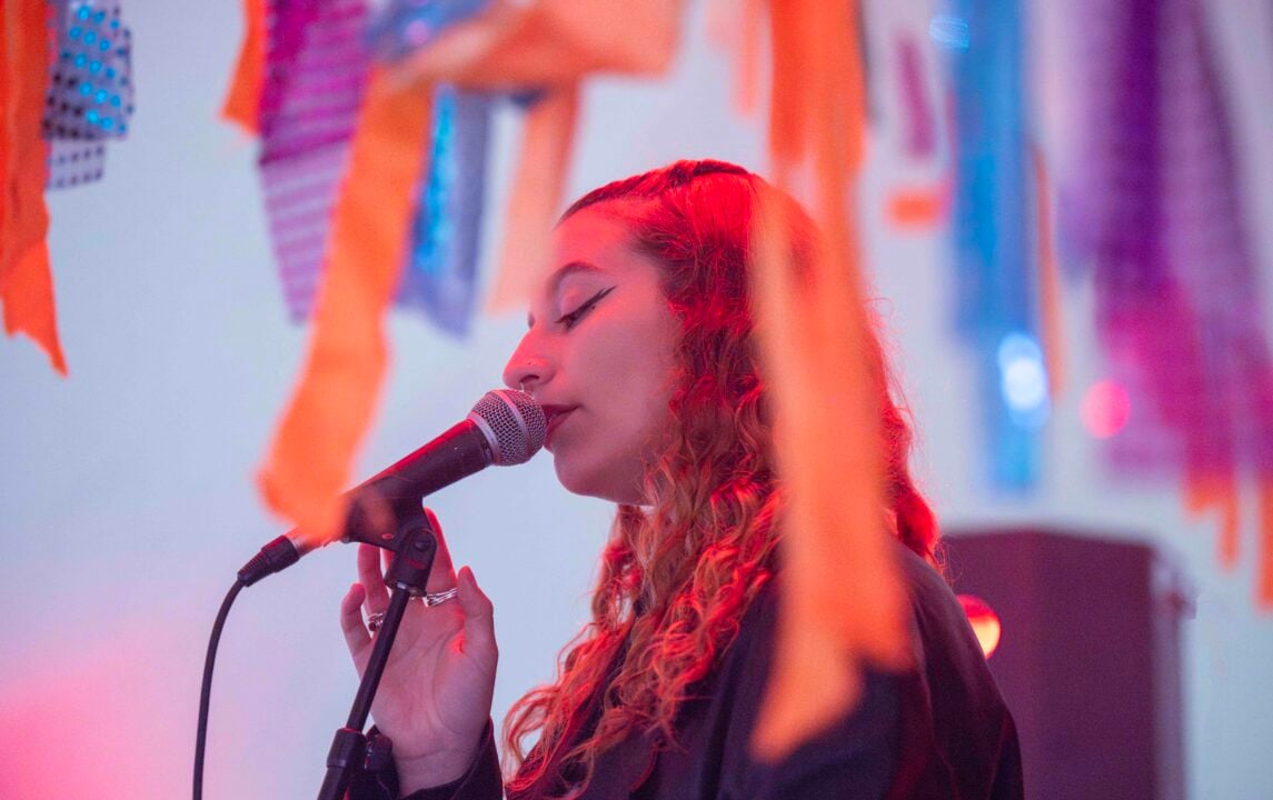 A close up of a woman singing amongst colourful streamer decorations