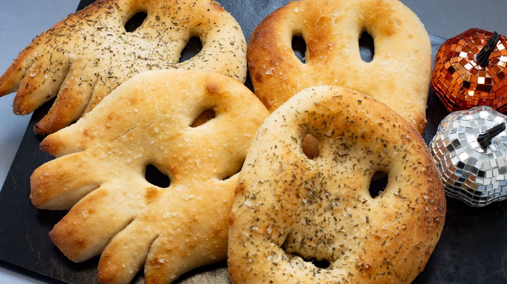 Breads shaped like ghosts. In the background are small pumpkins.