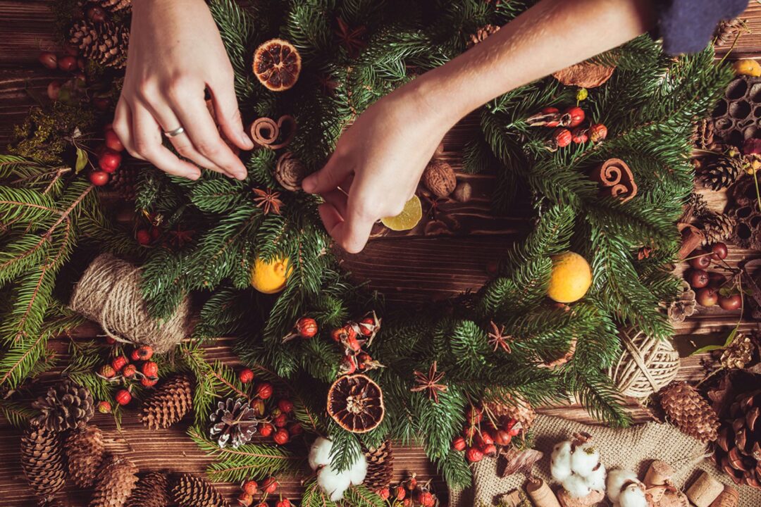 Close-up of a pair of hands adding decorations to a wreath.