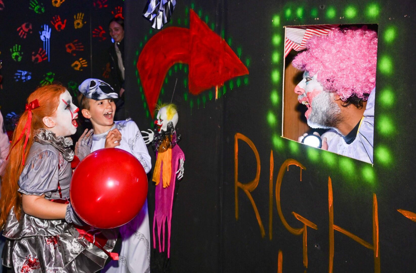 Two young children dressed in Halloween costumes screaming at clown