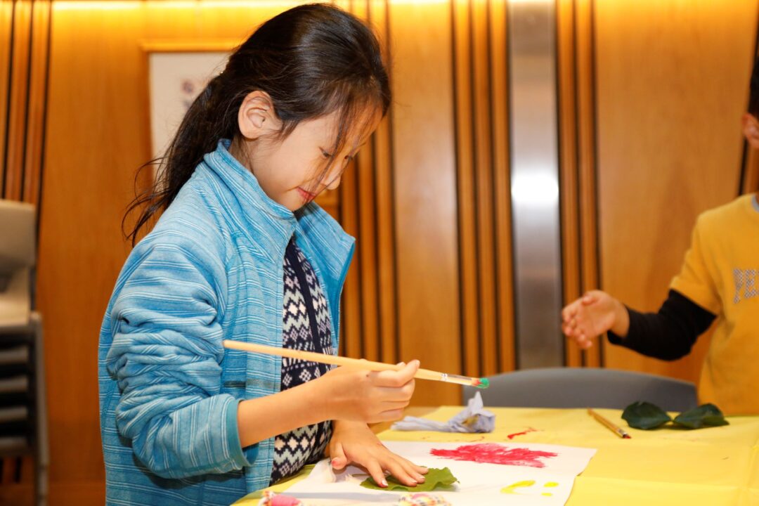 Young girl painting on a sheet of paper.