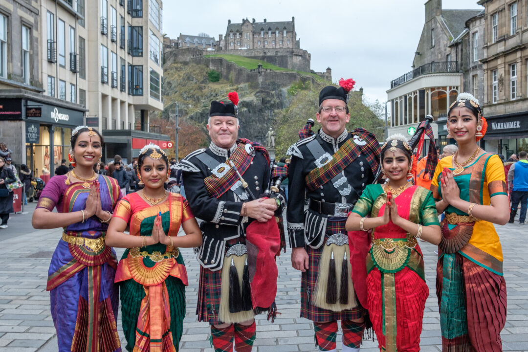 A group of 5 people: 2 are dressed in traditional Scottish dress, and 3 in traditional Indian dress.