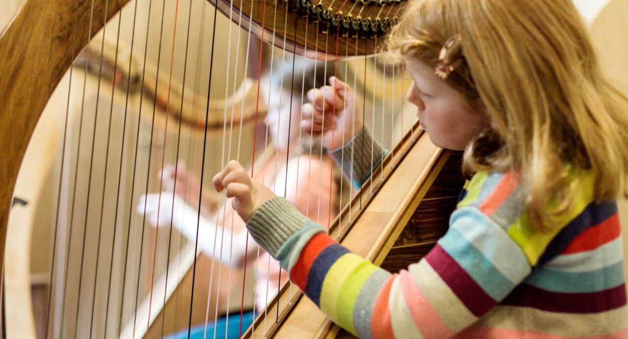 A young girl playing a harp.