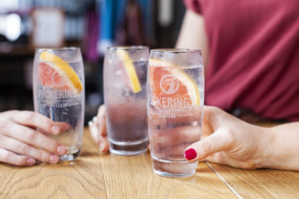 Three gin & tonics on a table with three people.