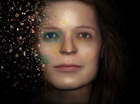 A female face covered on one side by copper, green and yellow squares