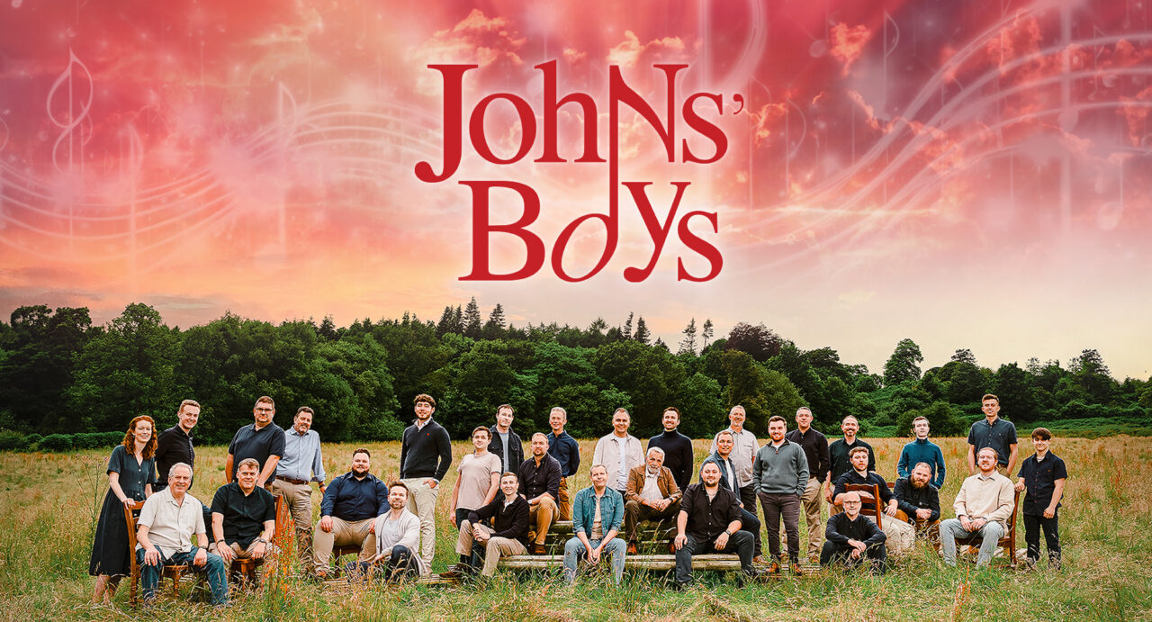 A large group of people, both standing and sitting, in a open grassy setting.