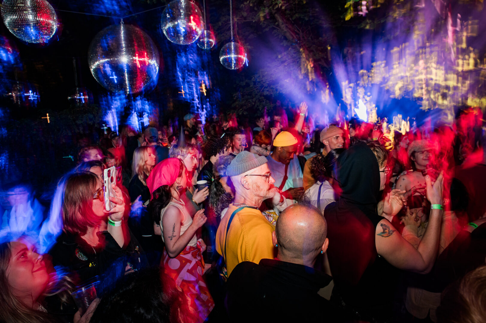 A crowd standing amongst disco balls and colourful lights