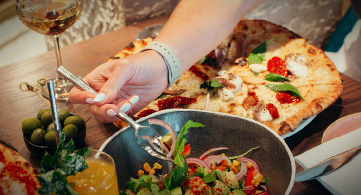 Lady's hand with fork lifting salad out of bowl