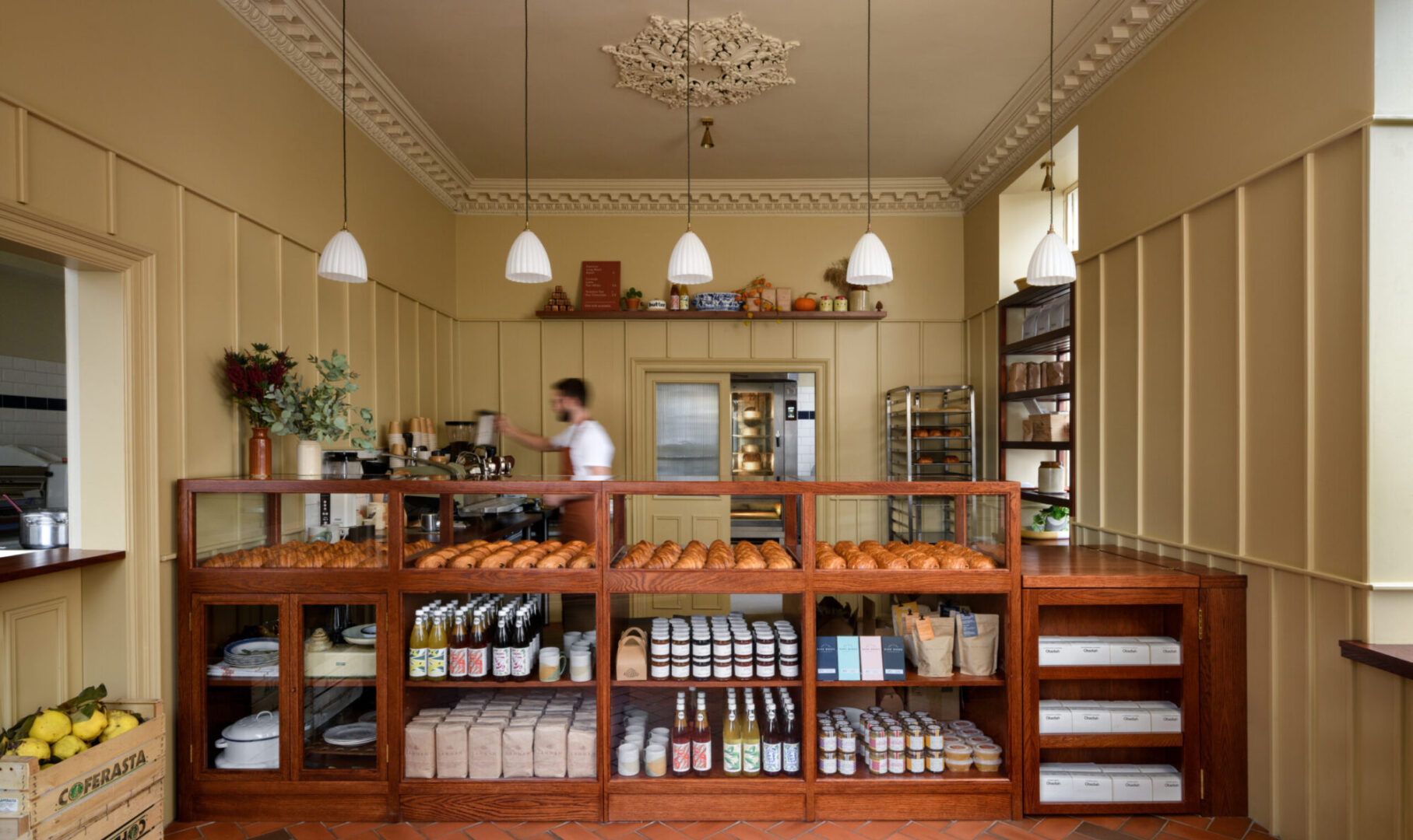A server at Lannan Bakery with Coffee machine and counter display of crossiants