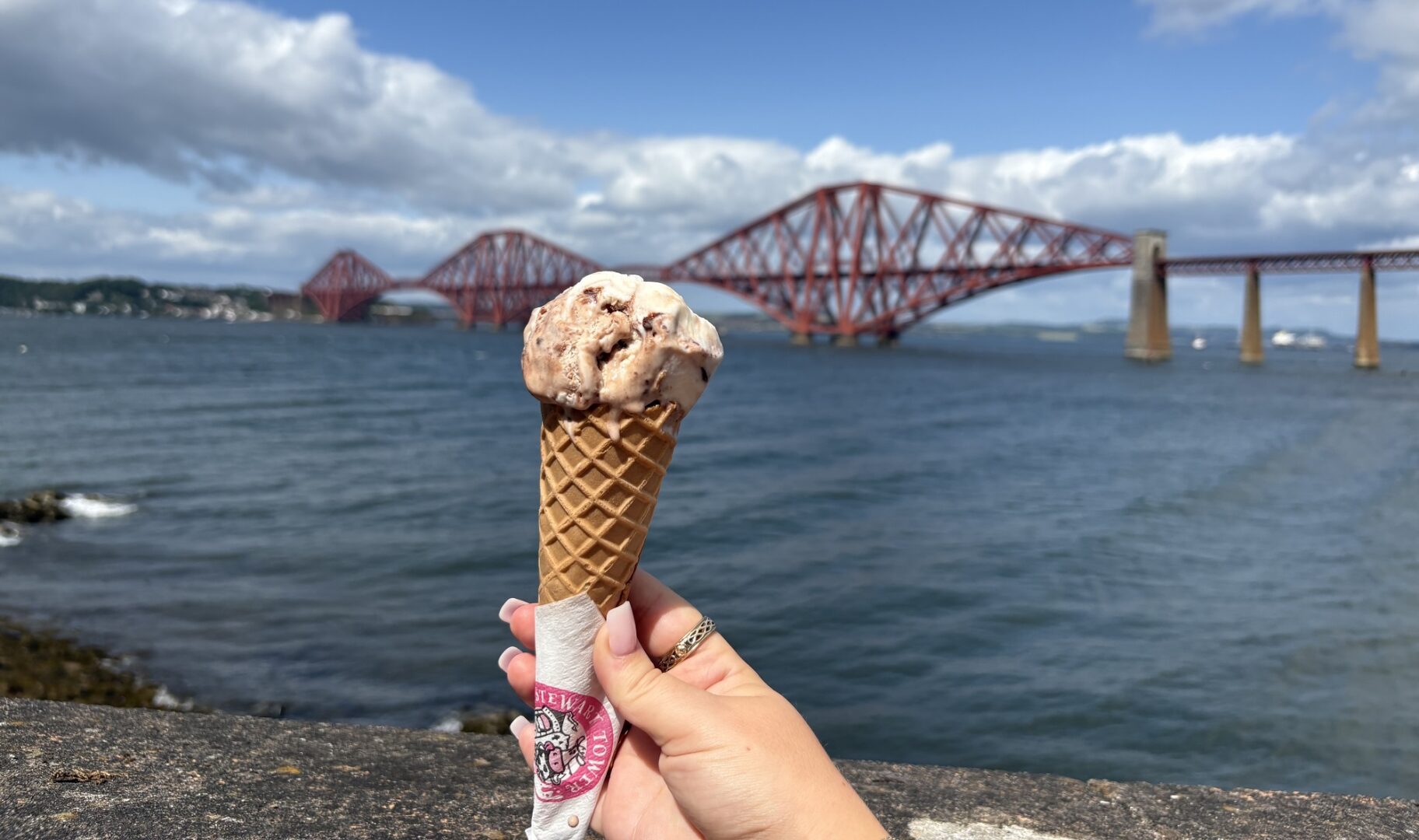 Little Parlour ice cream being held up with view of Forth Bridge in background
