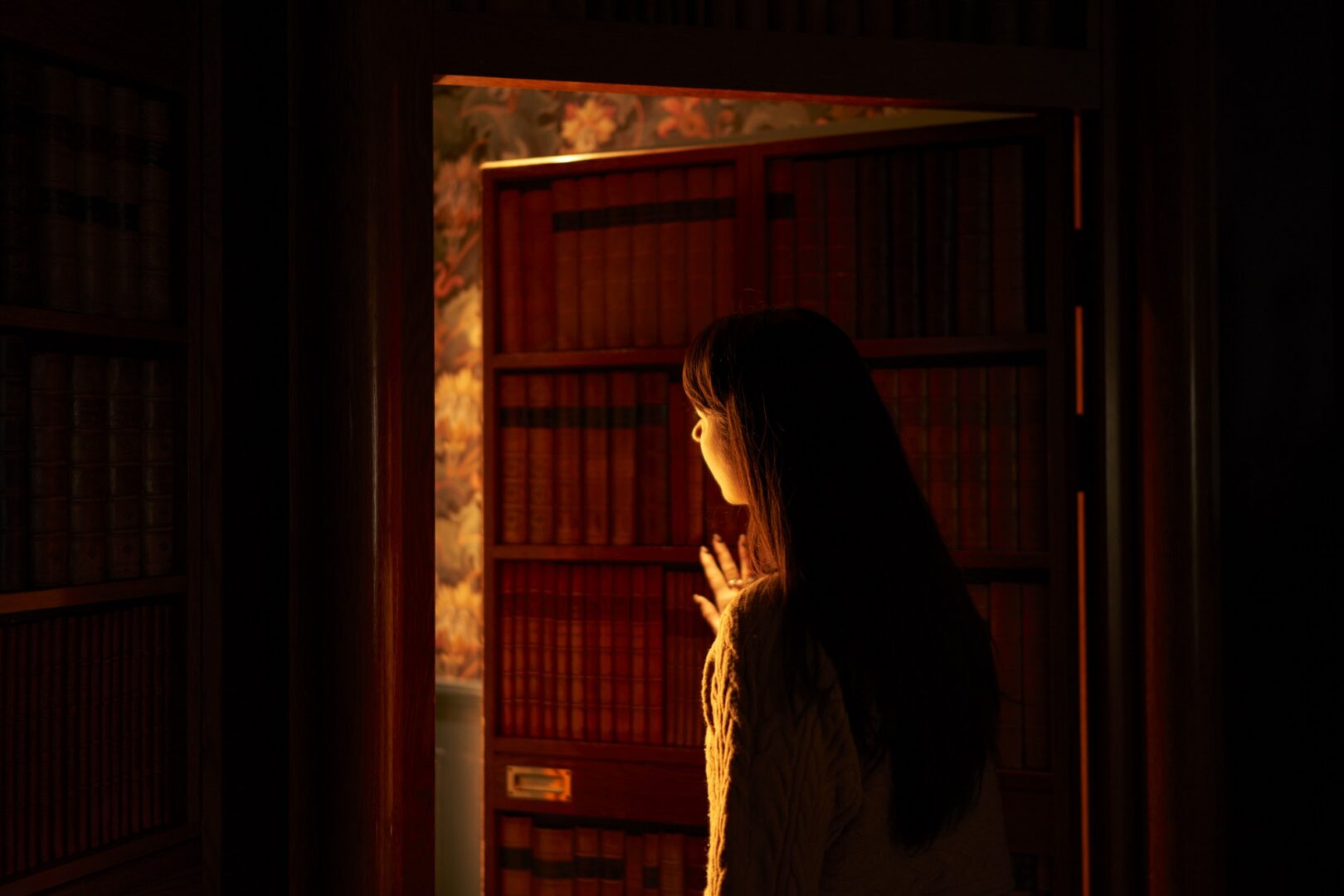 October Hero image of girl pushing door that looks like bookcase and revealing a hidden room