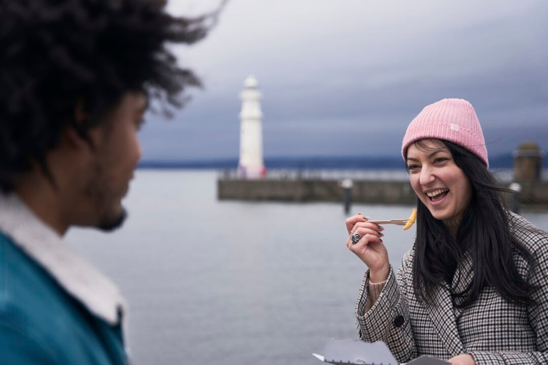 Person eating chips in front of lighthouse