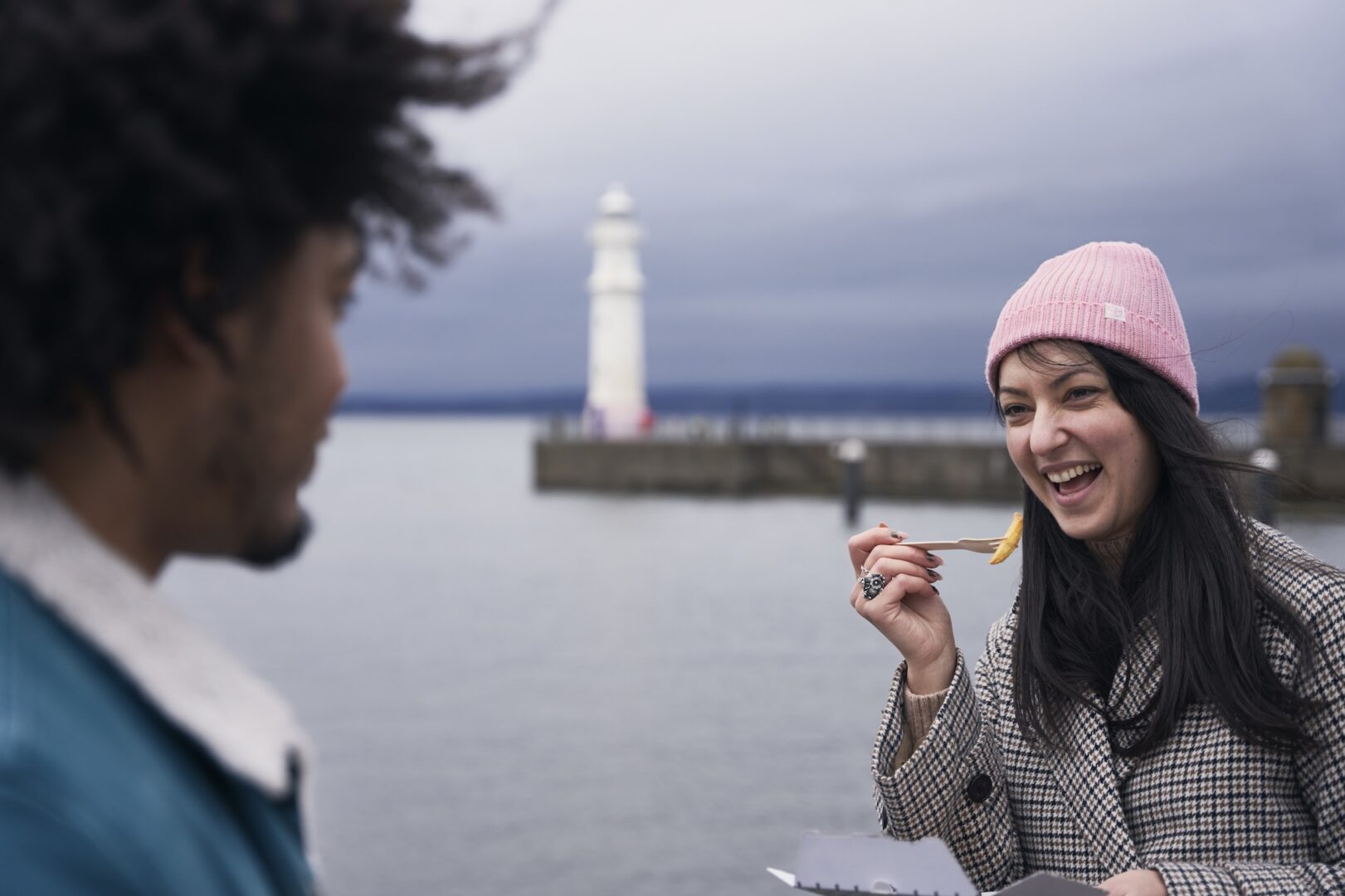 Person eating chips in front of lighthouse
