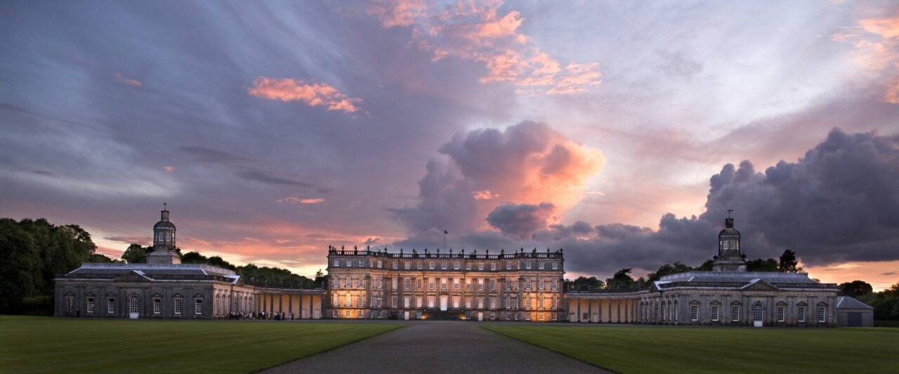 Image taken at twilight of the main entrance to the lit building taken from the long driveway.