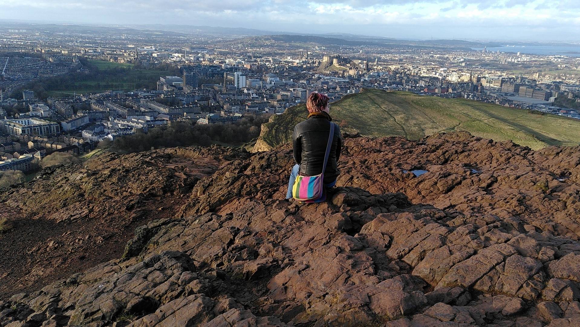 Person sitting at the summit of Arthur's Seat enjoying the view,© Angus Miller, Geowalks
