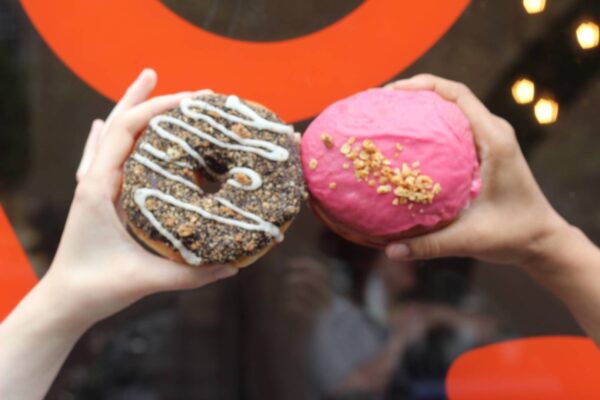 Two hands holding out donuts