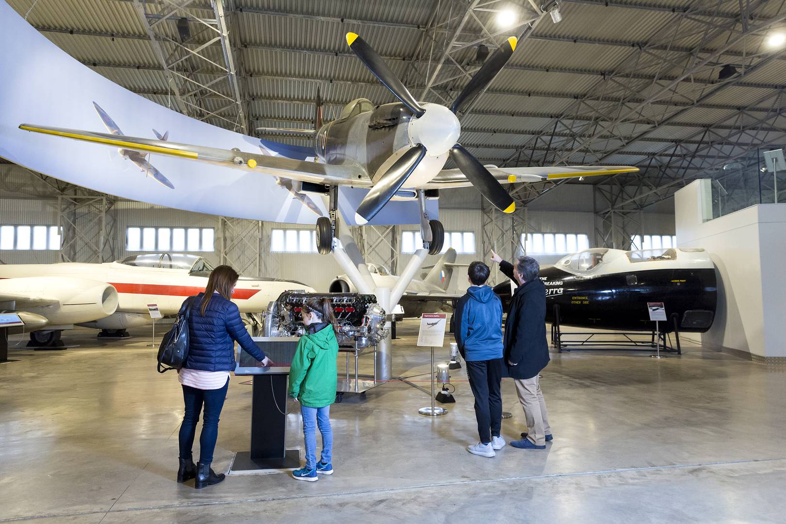 A family underneath a Spitfire aircraft in the Military Aviation Hangar at the National A Museum of Flight © Ruth Armstrong Photography,Image © Ruth Armstrong Photography