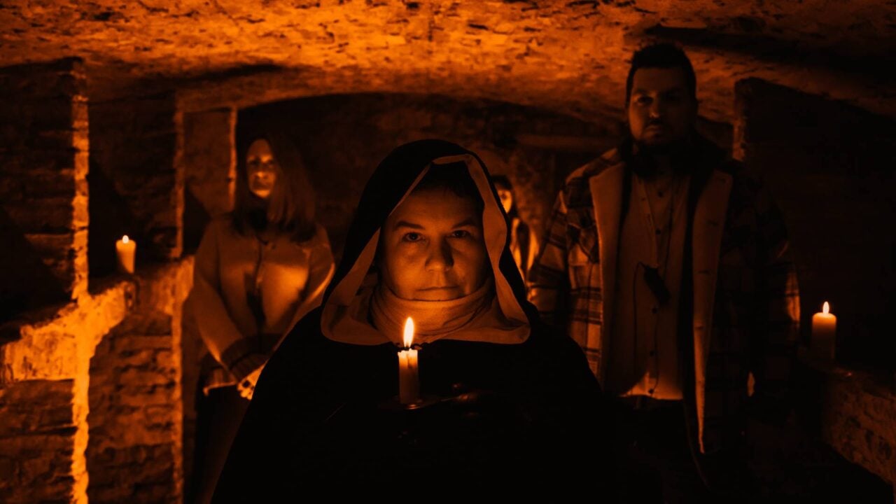 Tour Guides leading tour in vaults which are dark except for candle light.