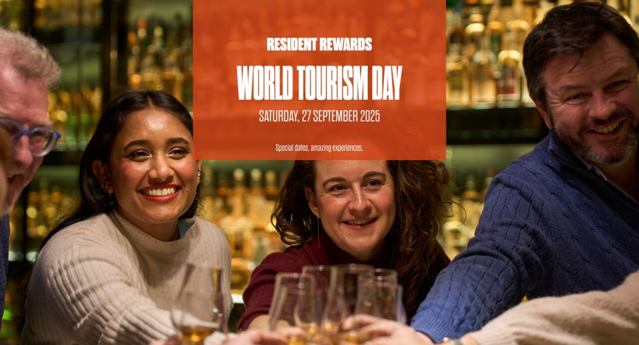 Group of people saying cheers and orange box with writing saying for World Tourism Resident Day