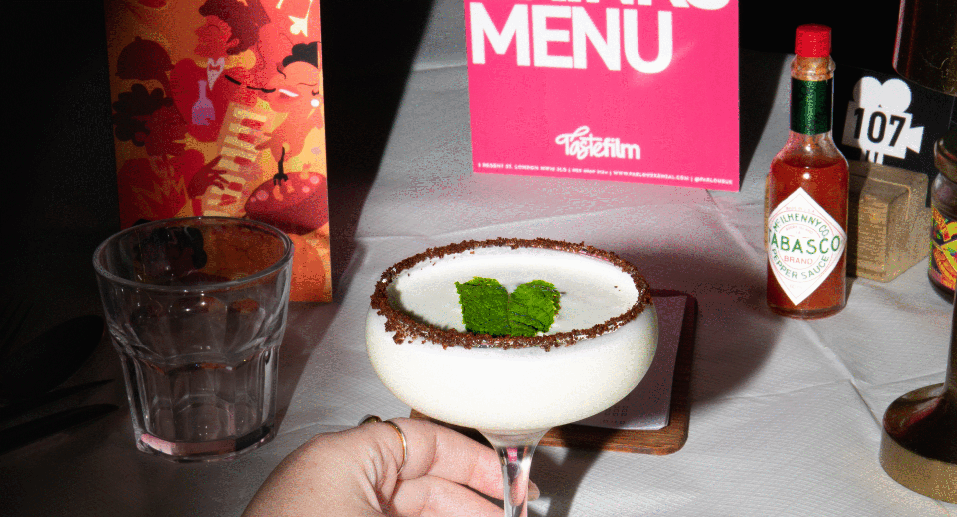 Table set with cocktail, menu, glass and condiments.